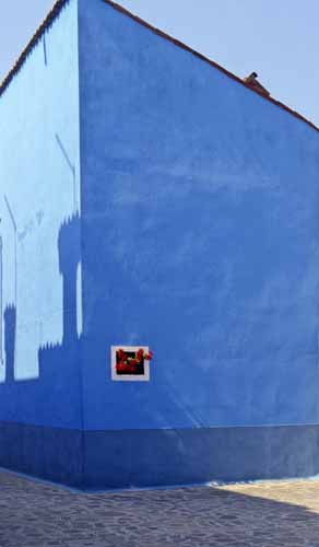 A blue wall with a tiny window full of red flowers - Burano in Venice, JBLArts photography